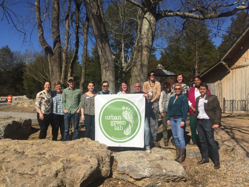 Group of Urban Green Lab supporters holding a sign with the previous Urban Green Lab logo of a footprint