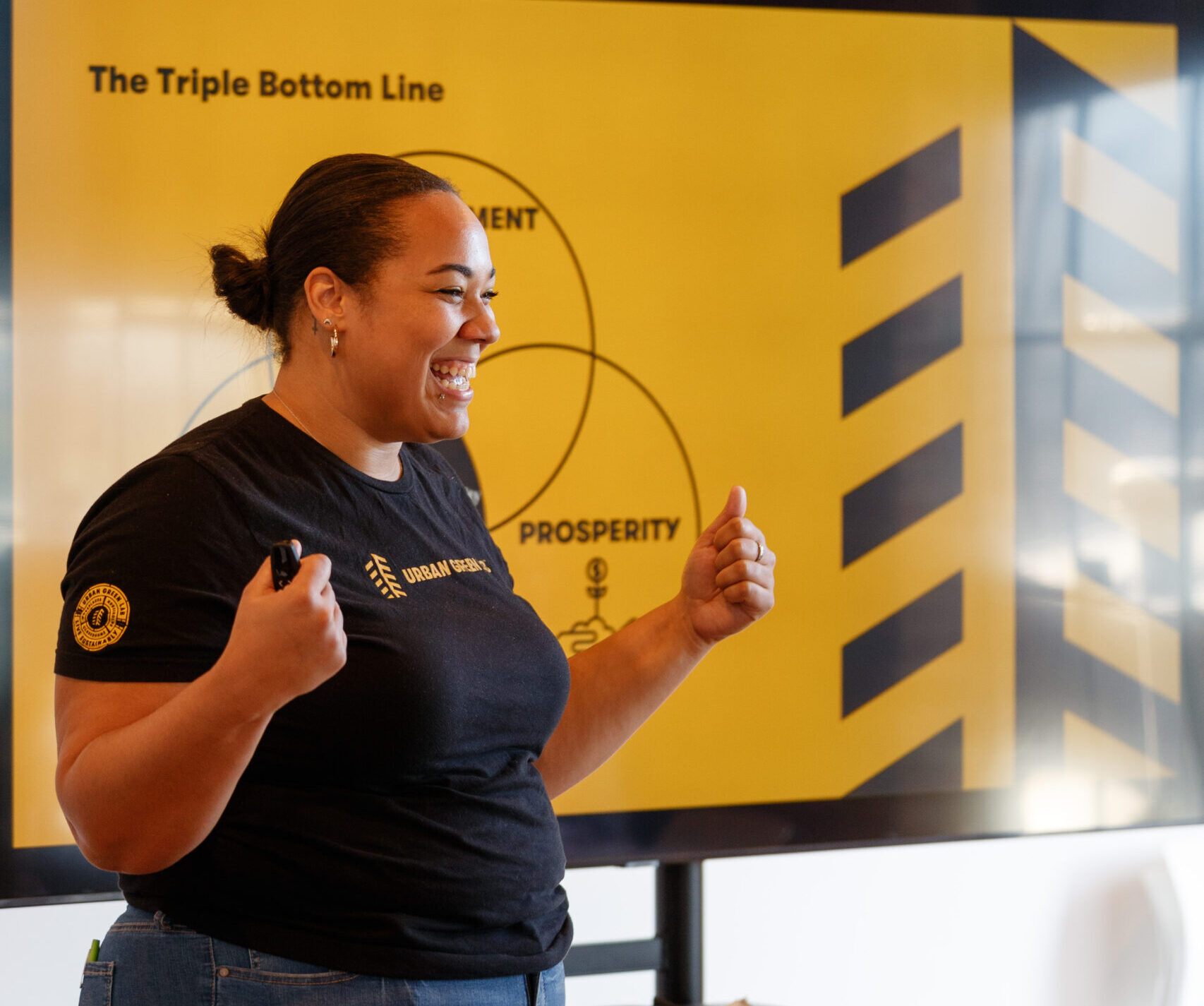 woman in a black t-shirt smiles in front of a powerpoint screen