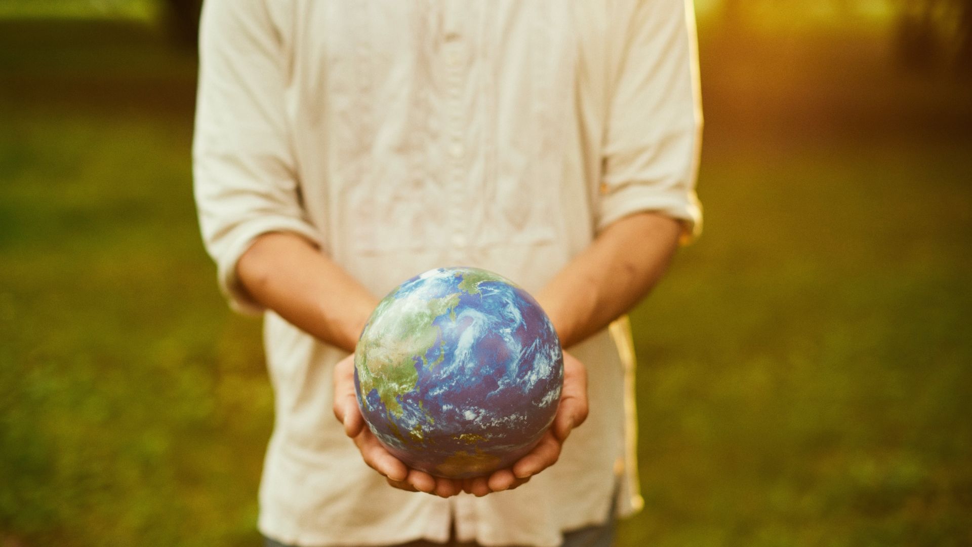 figure in linen shirt holds a globe of the world