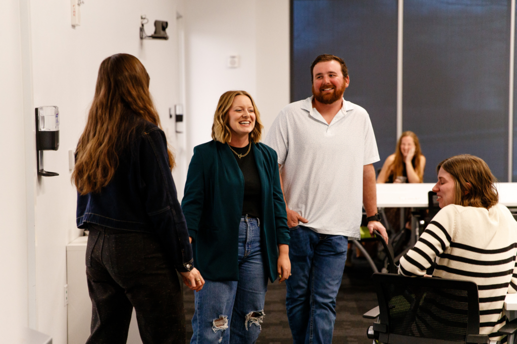 woman in blue blazer stands next to a man in a white golf shirt smiling