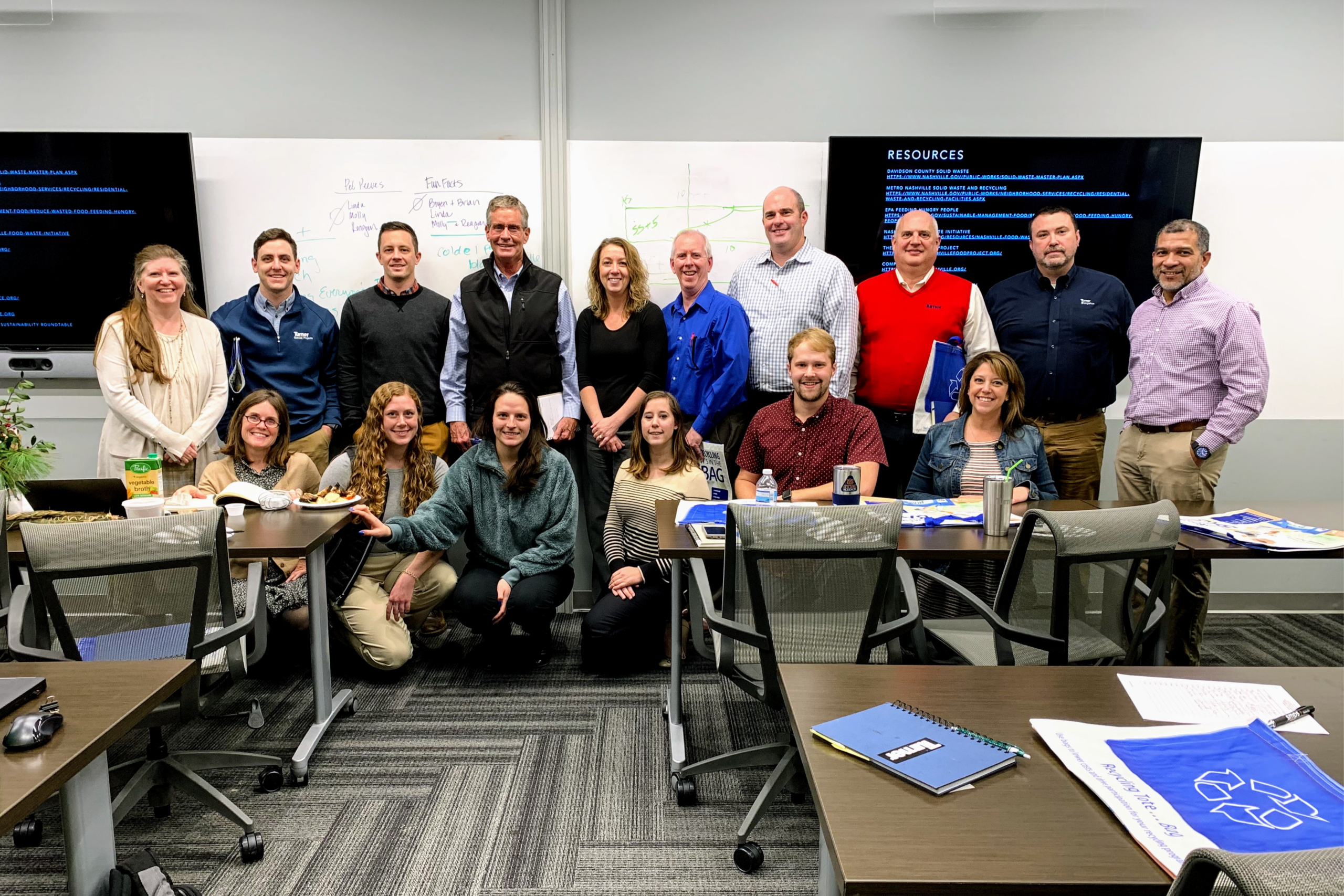 group of professionals pose for a photo at the end of a team training in front of a white board