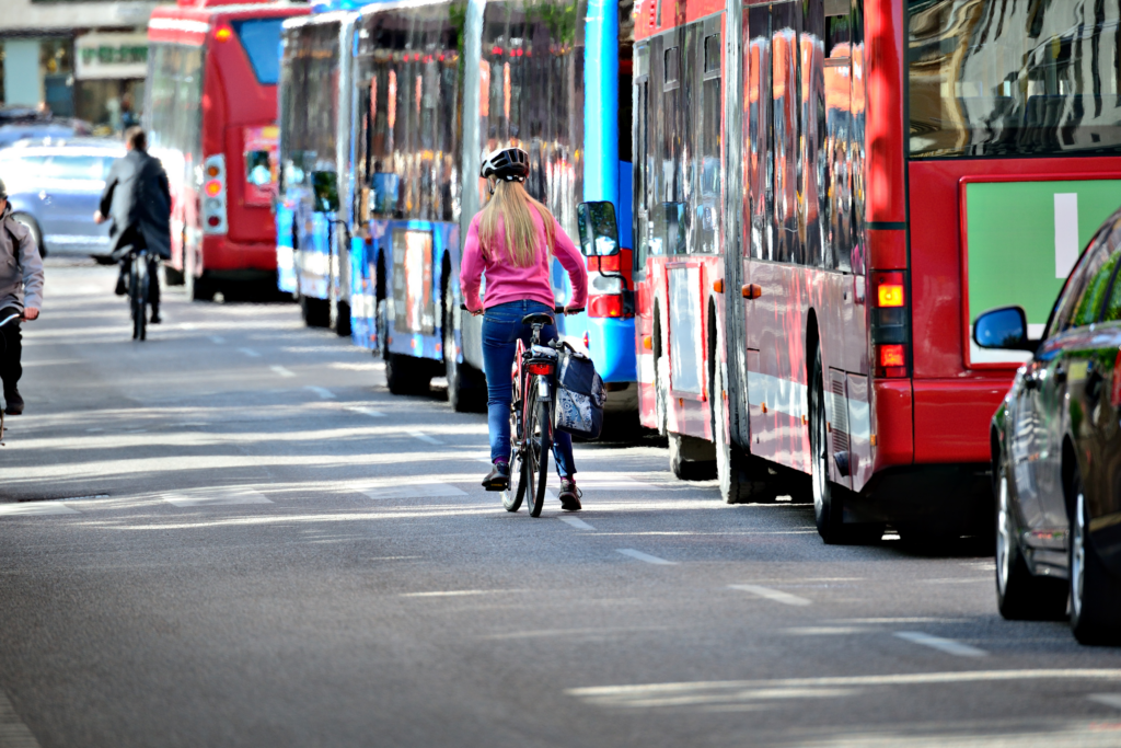 cyclists biking alongside a lane of buses