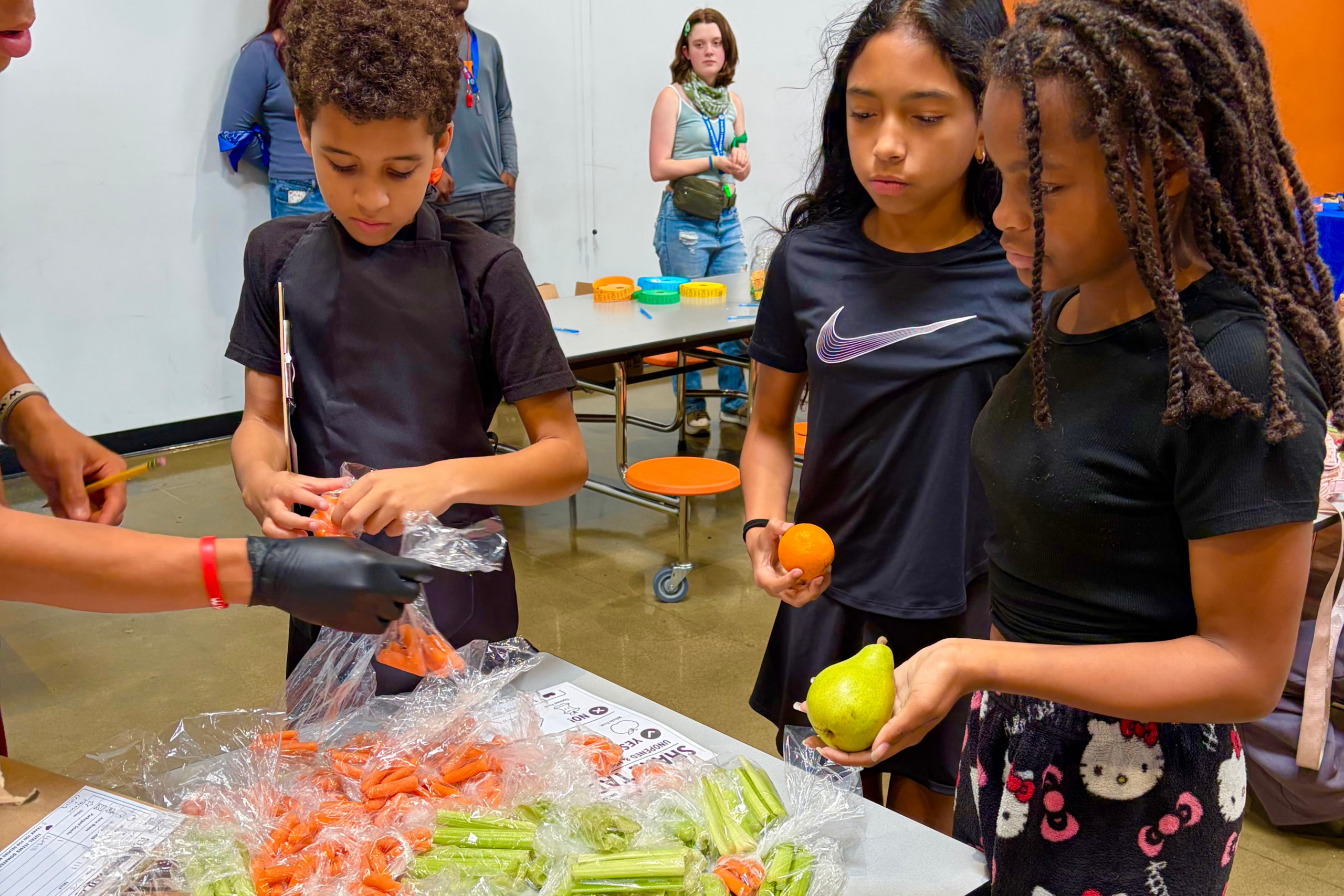 students standing over bags of food at a school cafeteria share table