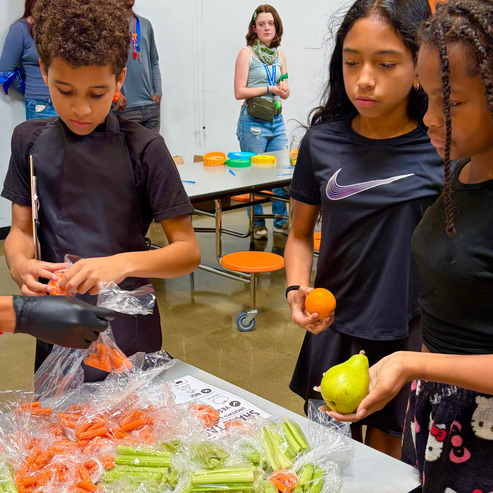 students standing over bags of food at a school cafeteria share table