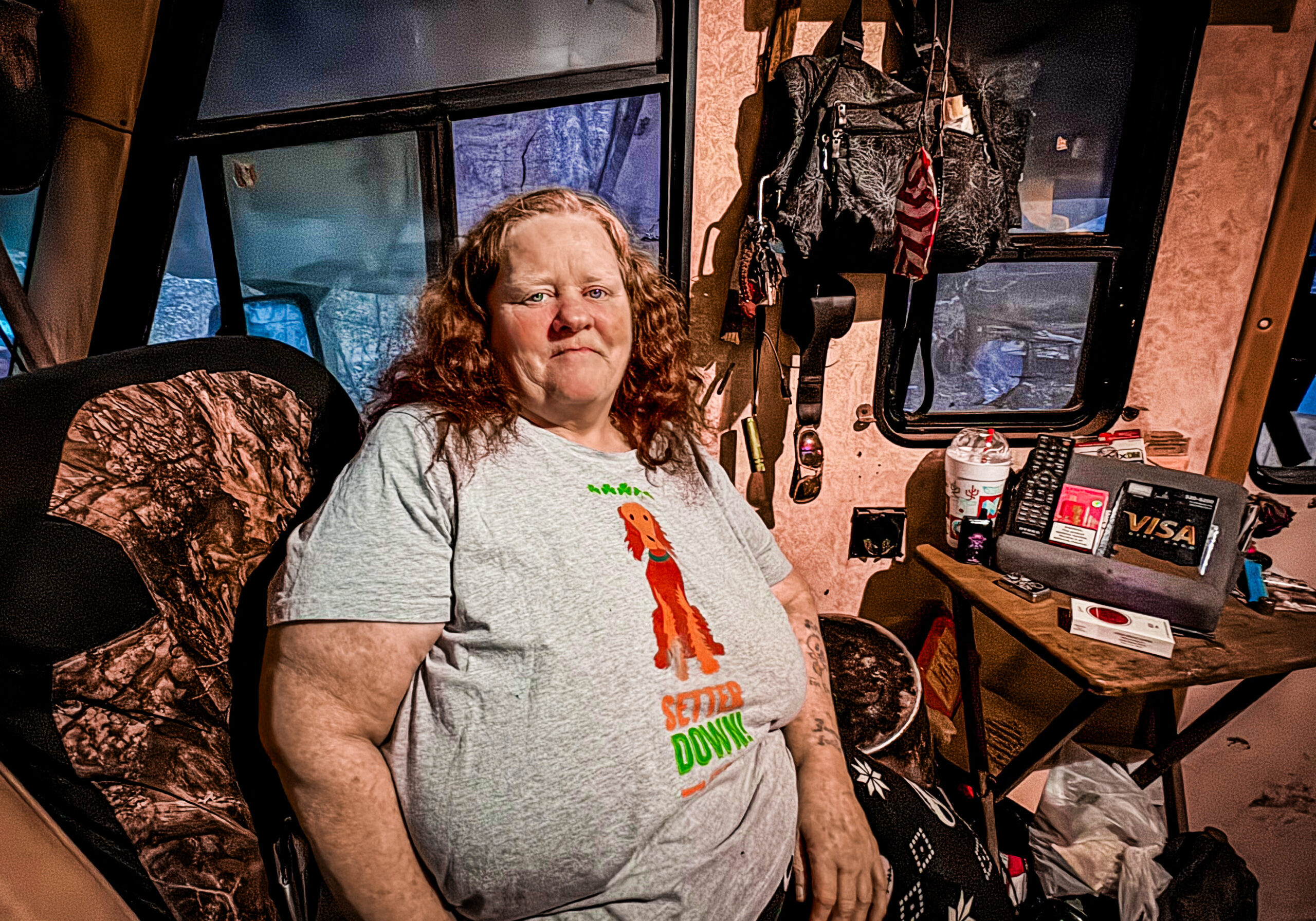 87e0a148-d203-450d-ab80-f41c98fa29c2 Red-headed woman sitting at a desk in front of a window