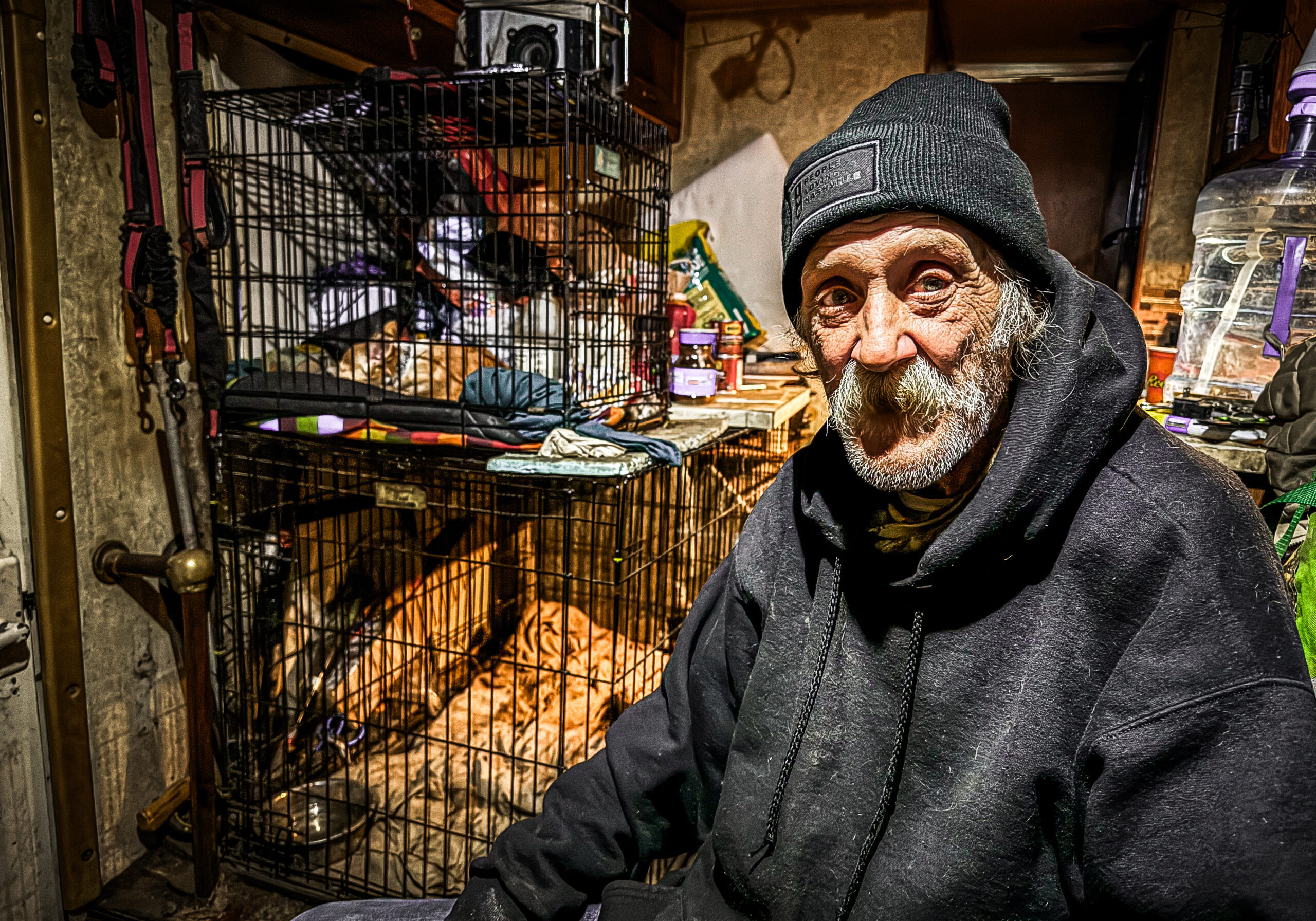Arthur_McQuiston Man in black coat and beanie hat in front of a wire shelf
