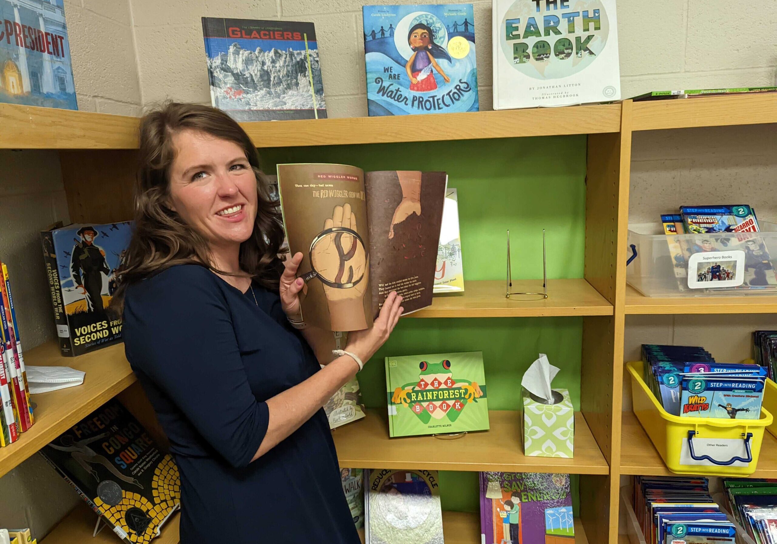 Teacher holds up a picture book about sustainability