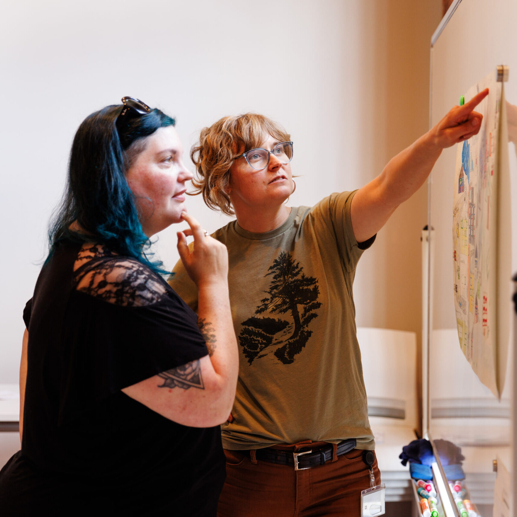 Two person looking at a poster with one person pointing at the poster