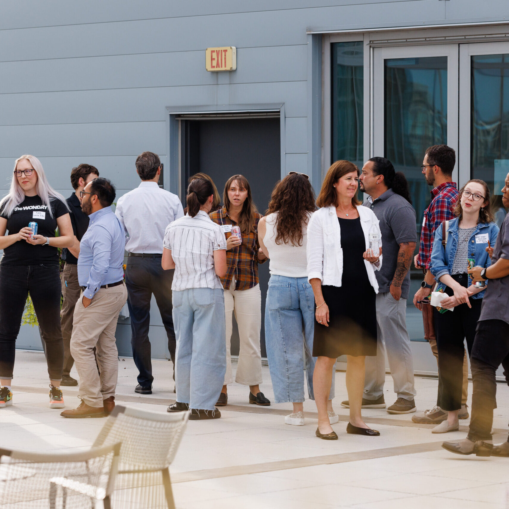 A group of professionally dressed people stands on an outdoor patio together