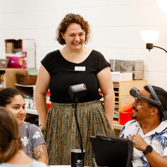 A woman laughing and talking to a table of teachers