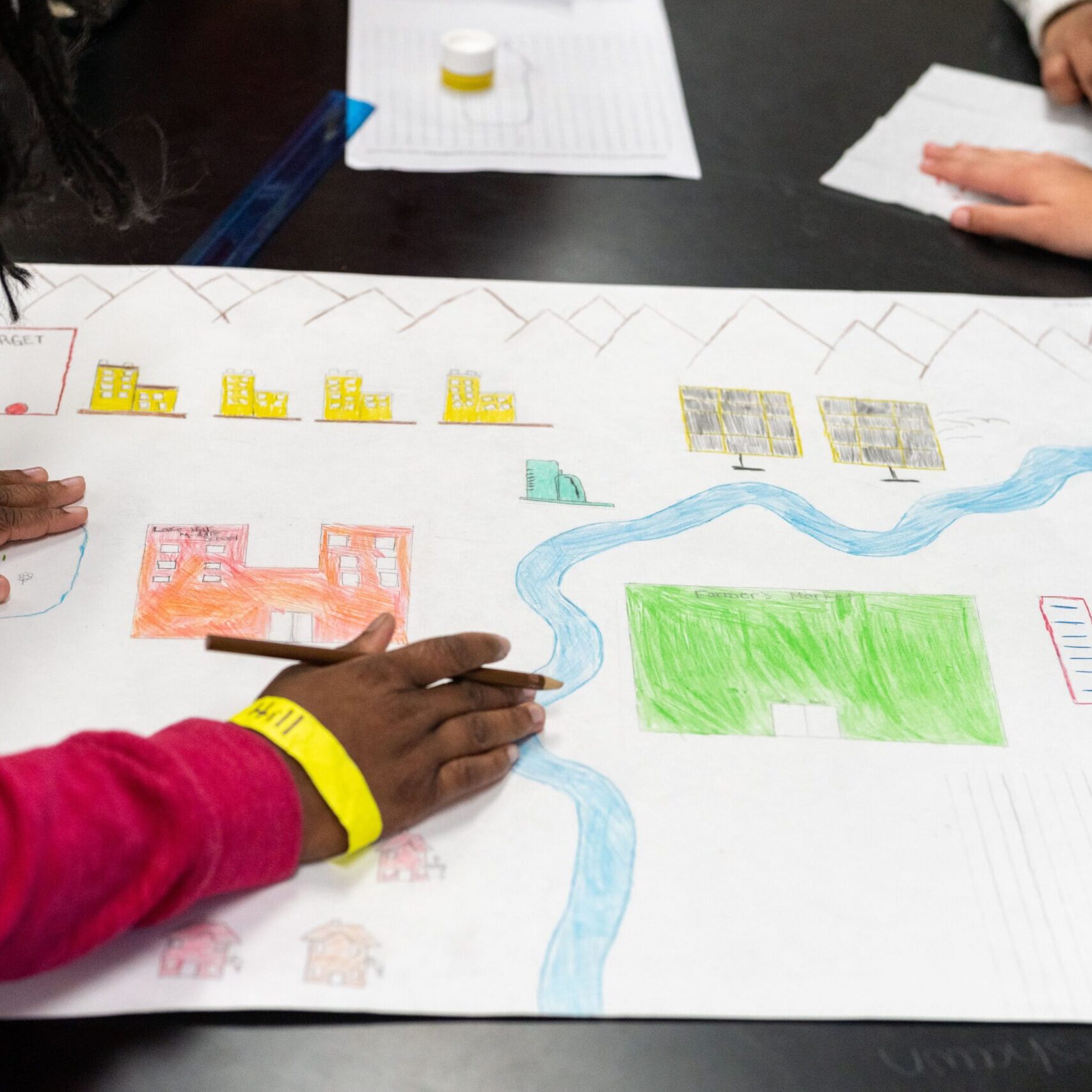 Students draw a city on a large posterboard